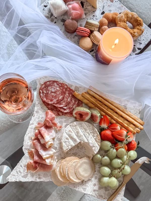 A grazing board of cured meats, cheeses, figs and grapes beside a glass of rosé