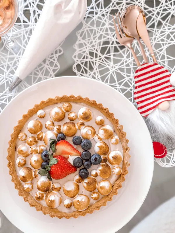 A berry-topped meringue tart on a festive table