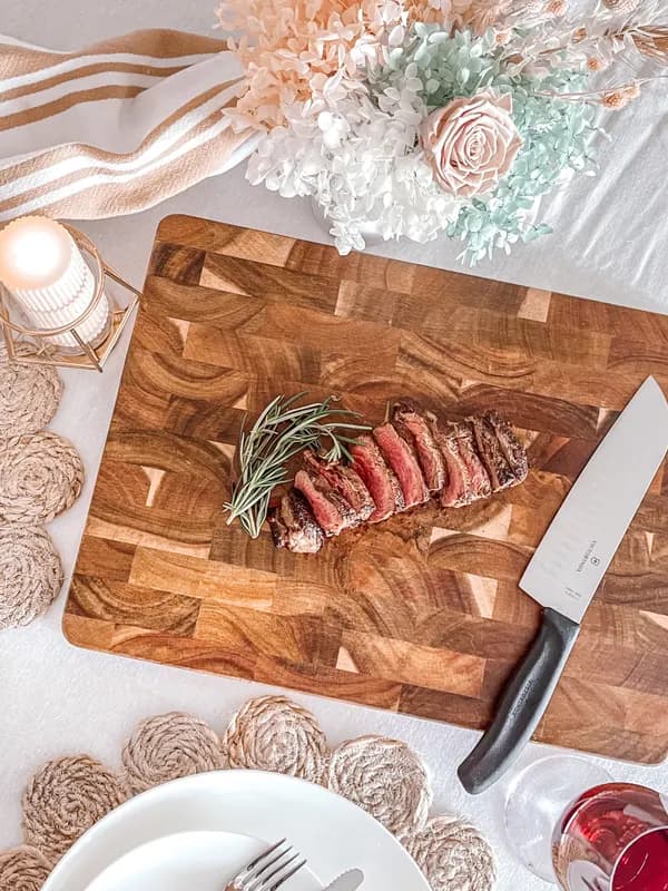 Sliced steak with rosemary on a wooden board