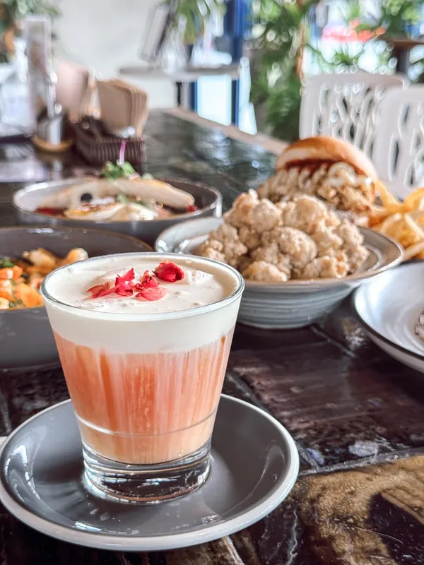 A layered strawberry latte topped with freeze-dried berries at a café table