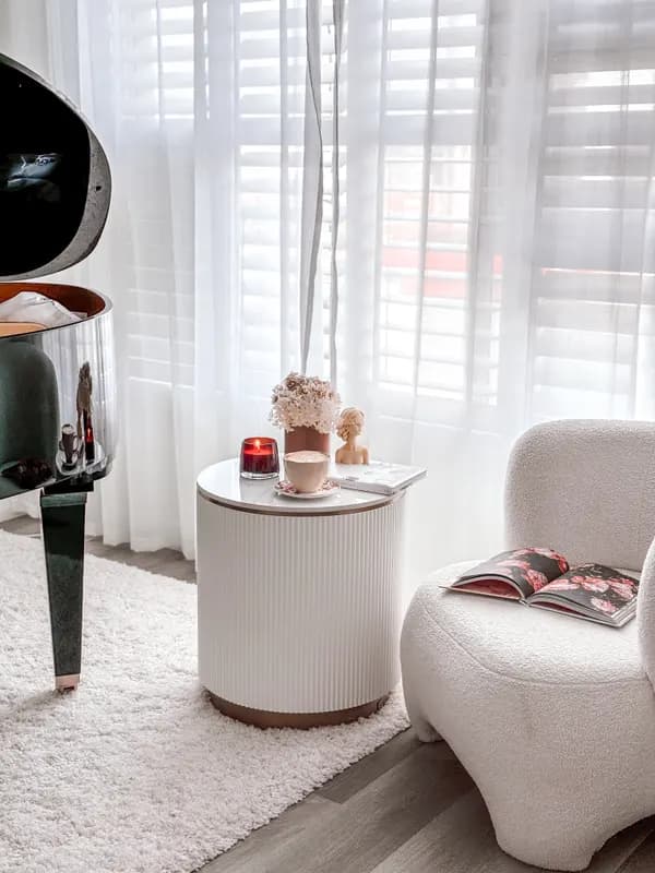 A bouclé armchair and side table by a sunlit window